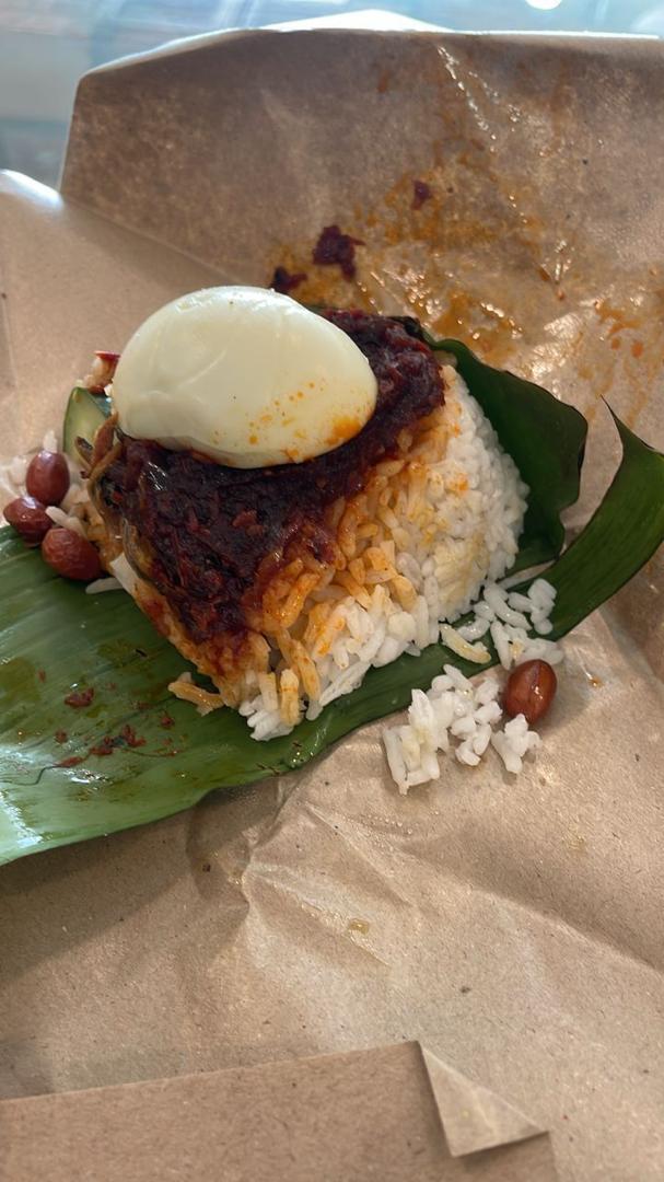 Bowl of glossy red chili sauce with whole chilies and lime halves on a banana leaf.